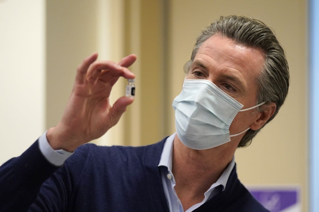 Newsom holds up a vial of the Pfizer-BioNTech vaccine at Kaiser Permanente Los Angeles Medical Center on December 14 in Los Angeles.