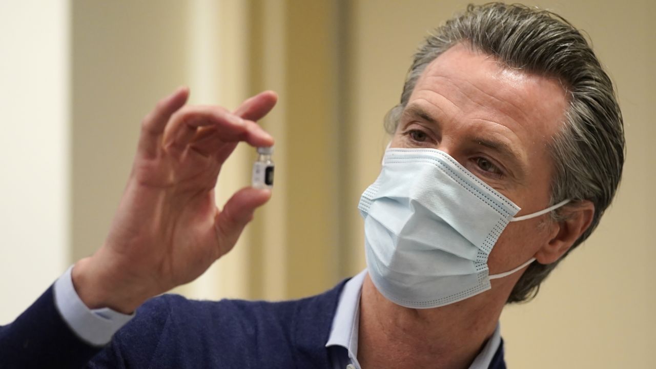 Newsom holds up a vial of the Pfizer-BioNTech vaccine at Kaiser Permanente Los Angeles Medical Center on December 14 in Los Angeles.