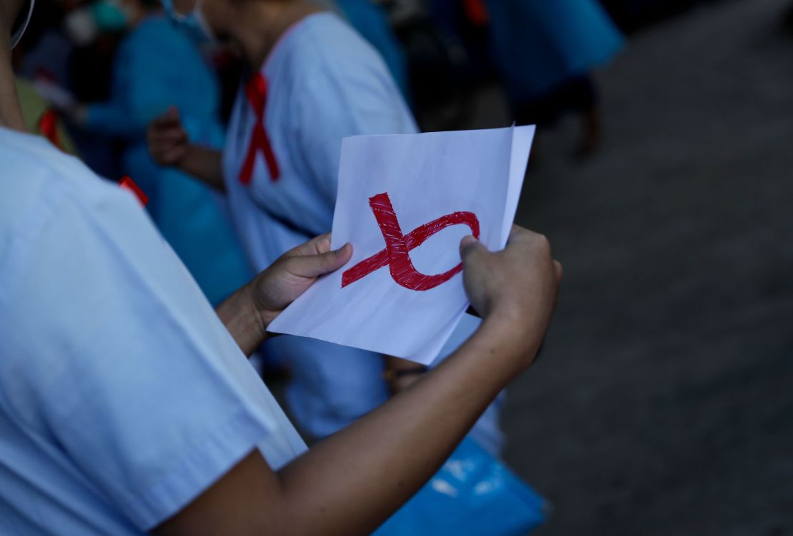 A medical staff holds a paper with the sign of red ribbon as a symbol of resistance against the military coup at Central Women's Hospital in Yangon, Myanmar, February 3, 2021. 