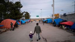 A man walks with his daugher at an asylum seekers camp near the Zaragoza bridge in Ciudad Juarez, Mexico, on December 11, 2019.