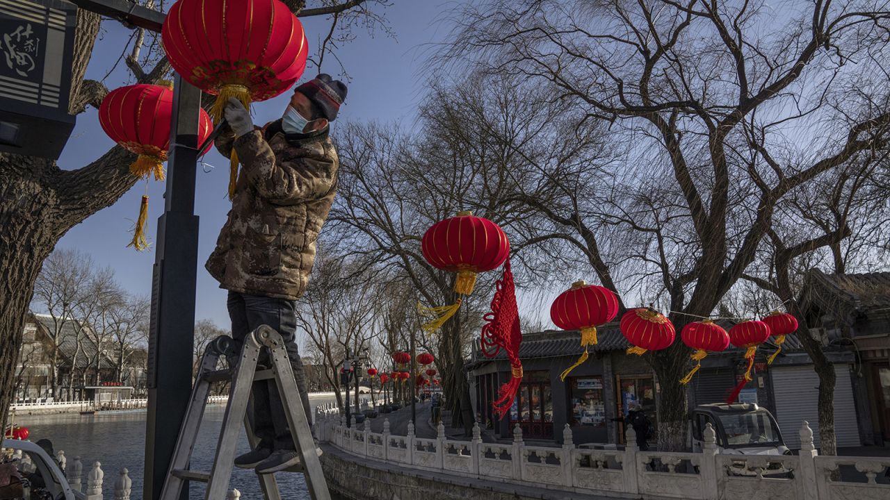 A worker hangs traditional red lanterns for the upcoming Spring Festival in a usually busy commercial and tourist area on February 3, 2021 in Beijing, China.