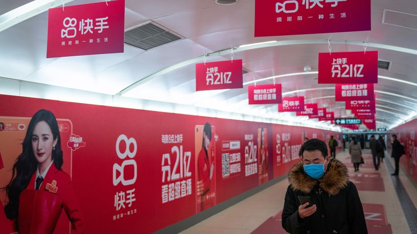 A passenger wearing a protective mask walks past Kuaishou Technology advertisements at a subway station in Beijing, China, on Wednesday, Feb. 3, 2021. Kuaishou Technology, the operator of China's most popular video service after ByteDance Ltd.'s Douyin, raised HK$42 billion ($5.4 billion) after pricing its Hong Kong initial public offering at the top of a marketed range. Photographer: Yan Cong/Bloomberg via Getty Images