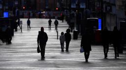 People walk past shops, temporarily closed down due to current coronavirus restrictions, in Leeds, northern England on January 6