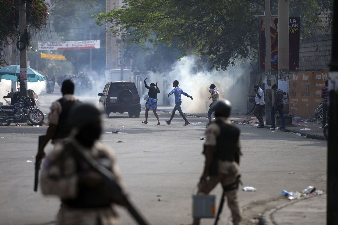 People walk across the street after the police fired tear gas during a nationwide strike demanding the resignation of Haitian President Jovenel Moise in Port-au-Prince, Haiti, on February 2.