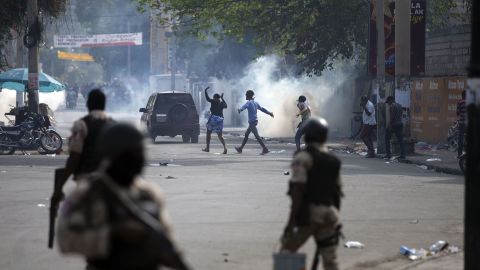 People walk across the street after the police fired tear gas during a nationwide strike demanding the resignation of Haitian President Jovenel Moise in Port-au-Prince, Haiti, on February 2.