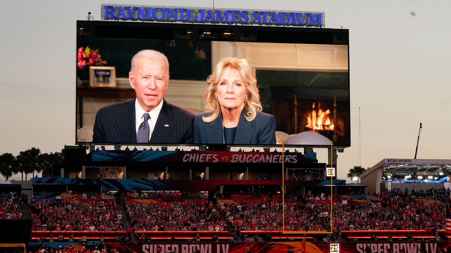 Fans watch a broadcast of President Joe Biden and first lady Jill Biden before the NFL Super Bowl 55 football game between the Kansas City Chiefs and Tampa Bay Buccaneers.