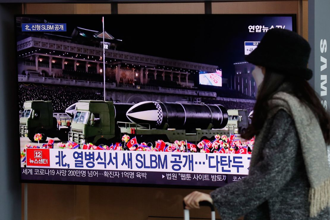 A woman wearing a face mask walks past in front of a TV screen showing a news program reporting about North Korea's military parade, at the Seoul Railway Station in Seoul, South Korea, on January 15.