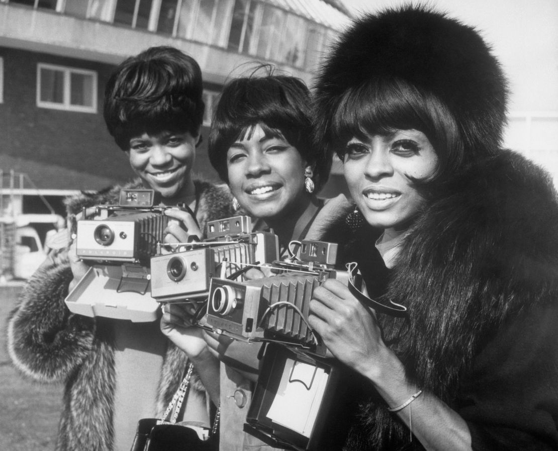 The Supremes (left to right, Florence Ballard, Mary Wilson, and Diana Ross) pose with their cameras as they arrive at London Airport.