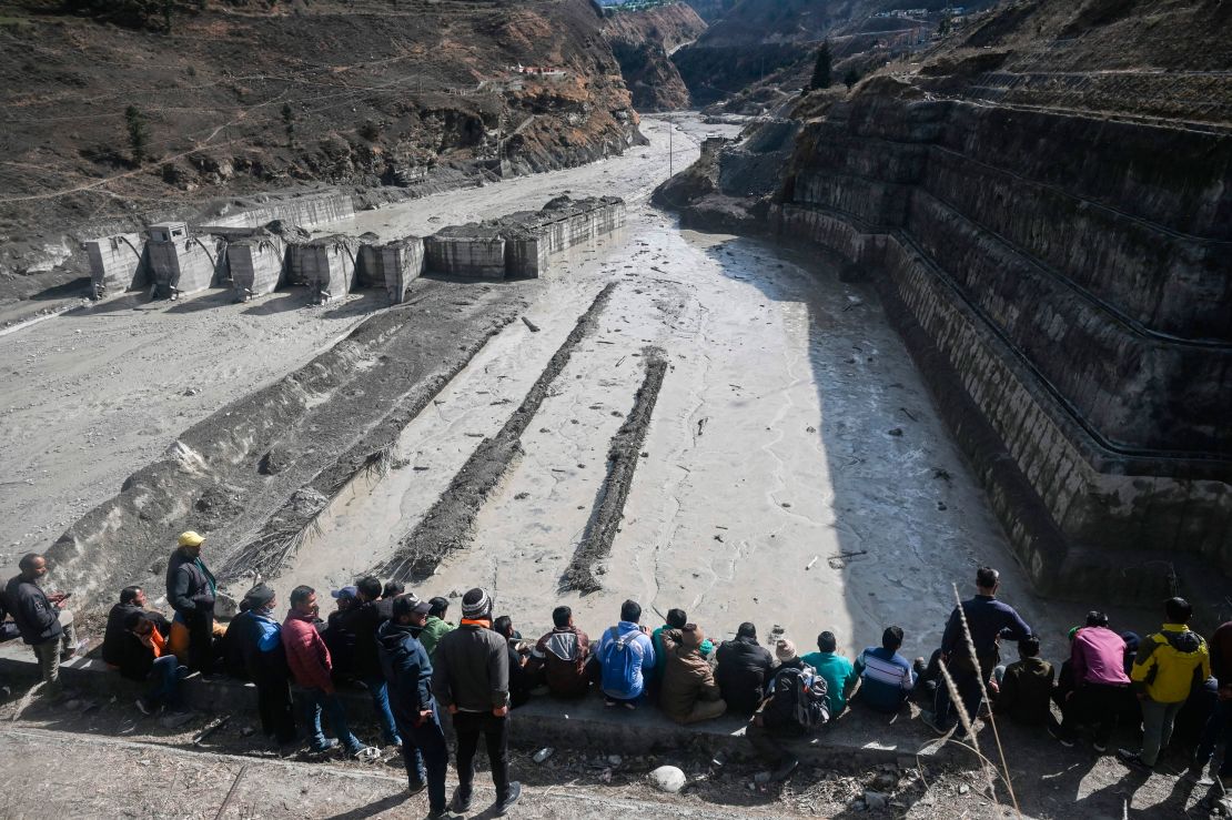 People look at the remains of a dam along a river in Tapovan of Chamoli district on February 9, 2021.