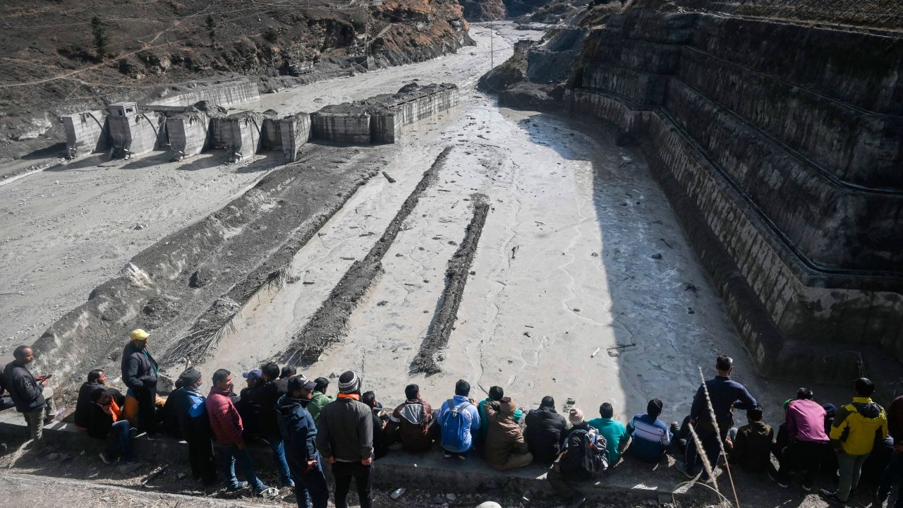 People look at the remains of a dam along a river in Tapovan of Chamoli district on Tuesday, destroyed after an avalanche.