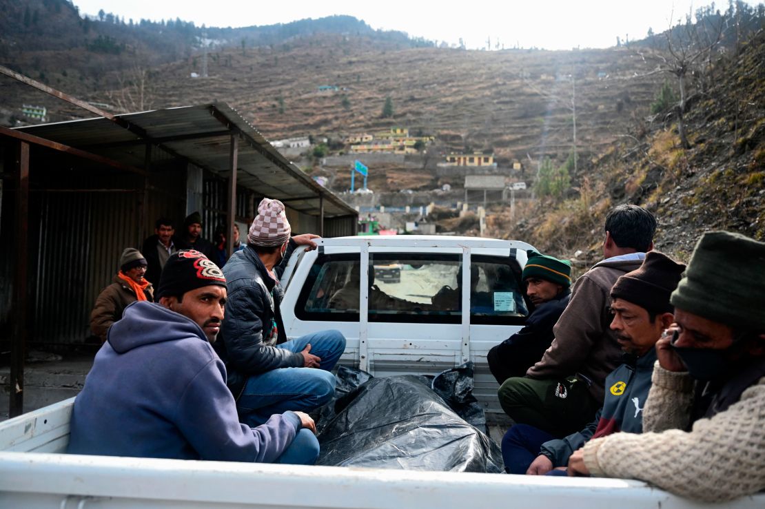 Relatives sit on the back a vehicle next to the body of a victim recovered from Raini village, outside a temporary morgue in Tapovan of Chamoli district on February 9, 2021.