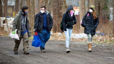 A resident, left, of the homeless encampment known as the Jungle, walks with Matt Dankanich, a community health worker for REACH Medical; a friend of the resident and Deb Wilke, right, the homeless crisis alleviation coordinator for Second Wind Cottages, accompany them.