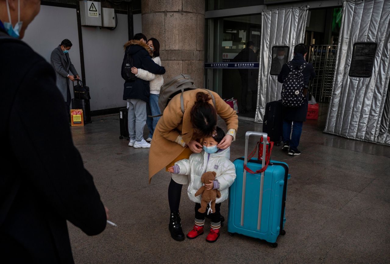 A woman adjusts a child's protective mask as they wait to board a train in Beijing on February 10.