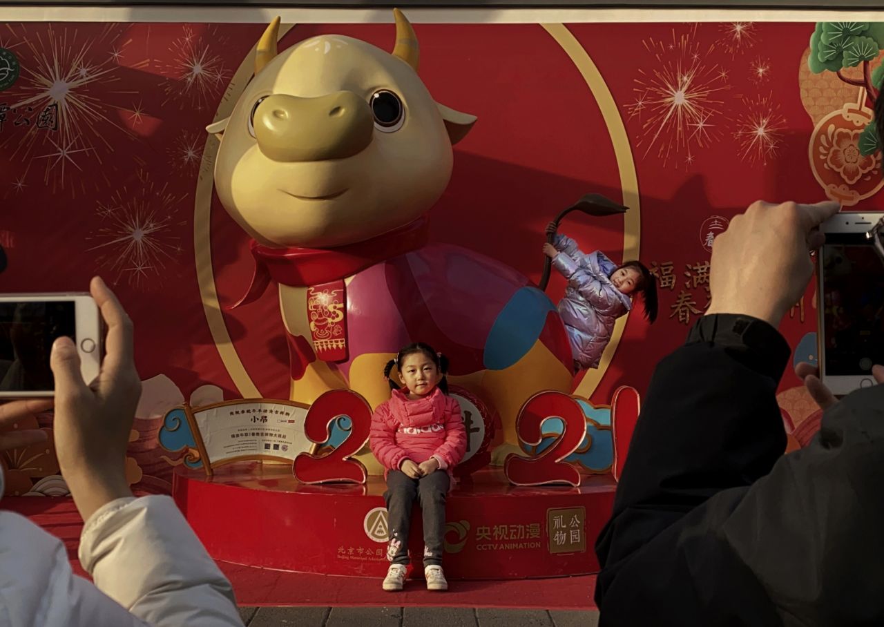 Girls pose in front of a cartoon ox in Beijing on February 6.