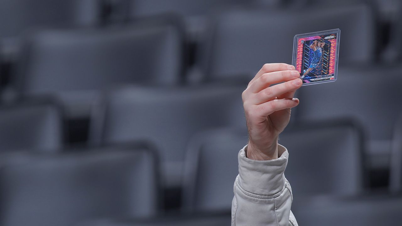 A fan holds up trading cards of Minnesota Timberwolves players prior to a game on Feb. 3, 2020.