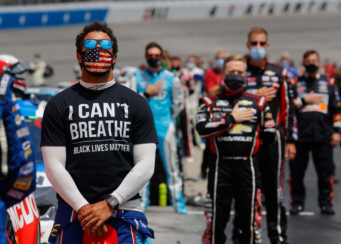 Bubba Wallace wears a "I Can't Breathe - Black Lives Matter" T-shirt under his fire suit in solidarity with protesters around the world taking to the streets after the death of George Floyd on May 25 while in the custody of Minneapolis, Minnesota police, stands during the national anthem prior to the NASCAR Cup Series Folds of Honor QuikTrip 500 at Atlanta Motor Speedway on June 07, 2020 in Hampton, Georgia.
