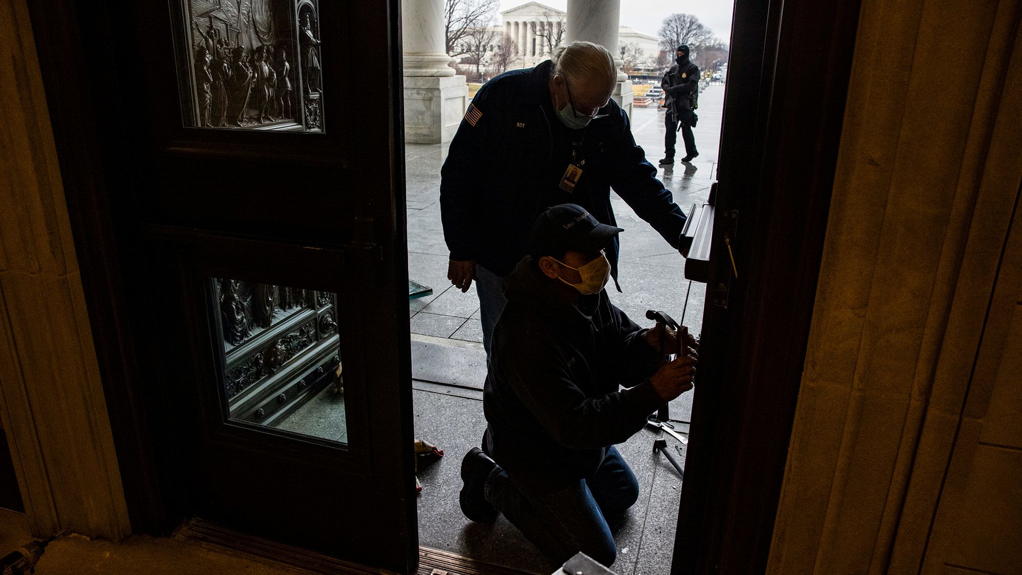 Workers replace window panes on Capitol doors that were damaged in last month's riot.
