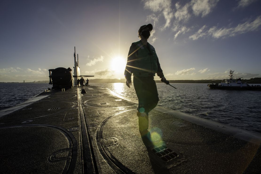 A sailor assigned to the guided-missile submarine USS Ohio walks along the top side of the vessel in Apra Harbor, Guam.