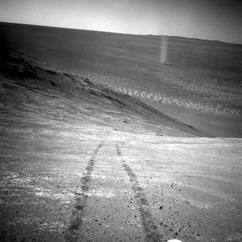 From its perch high on a ridge, Opportunity recorded this 2016 image of a Martian dust devil twisting through the valley below. The view looks back at the rover's tracks leading up the north-facing slope of Knudsen Ridge, which forms part of the southern edge of Marathon Valley.