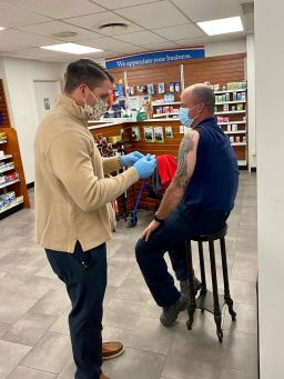 Pharmacist Adam Bayer administers a coronavirus vaccine. His pharmacy is one of many that are involved in the Federal Retail Pharmacy Program that rolled out this week. 