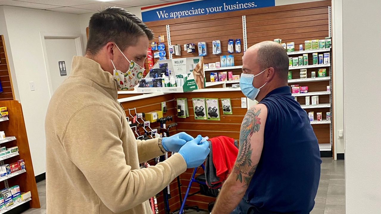 Pharmacist Adam Bayer administers a coronavirus vaccine. His pharmacy is one of many that are involved in the Federal Retail Pharmacy Program that rolled out this week. 