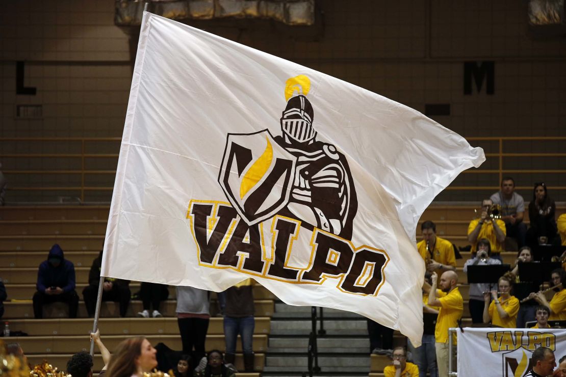 A Valparaiso University cheerleader waves a Valparaiso Crusaders flag.