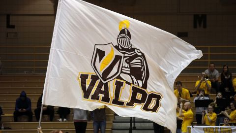 A Valparaiso University cheerleader waves a Valparaiso Crusaders flag.