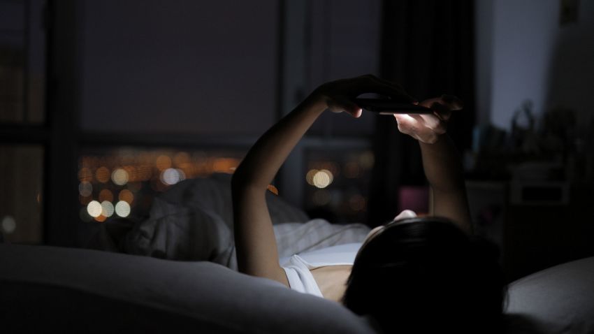 Woman watching on cellphone and lying on bed