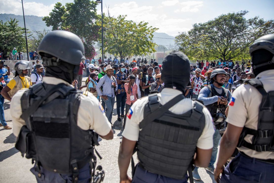 Journalists face armed police as they gather outside the Departmental Directorate of Police to file a complaint after they were hit with tear gas in Port-au-Prince, February 10, 2021. 