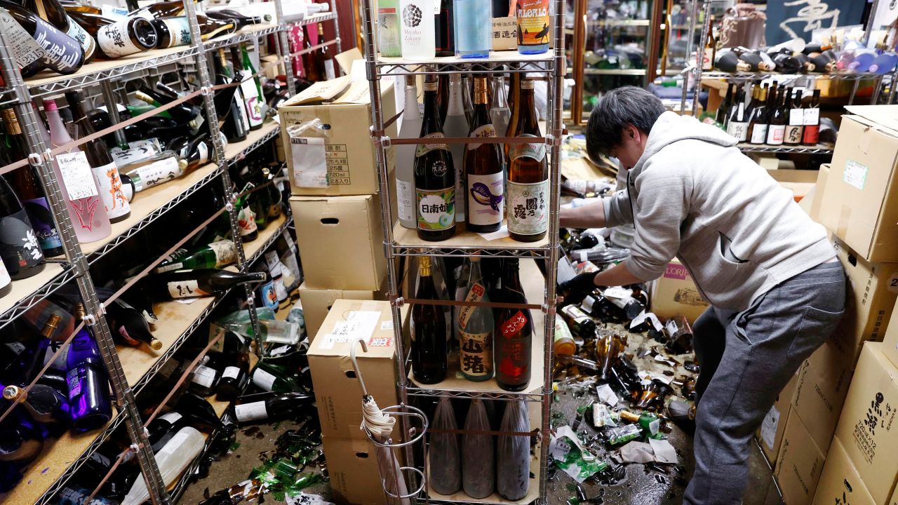 A liquor shop's manager clears damaged bottles following Saturday's quake.