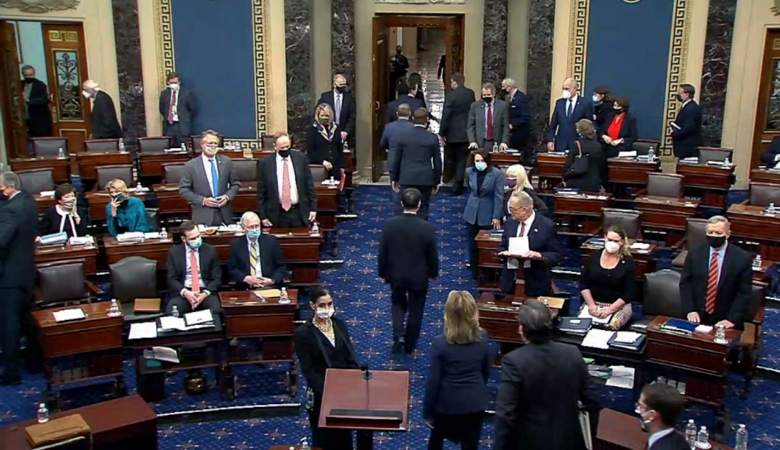 The House impeachment managers are escorted out of the Senate Chamber after the final vote Saturday.