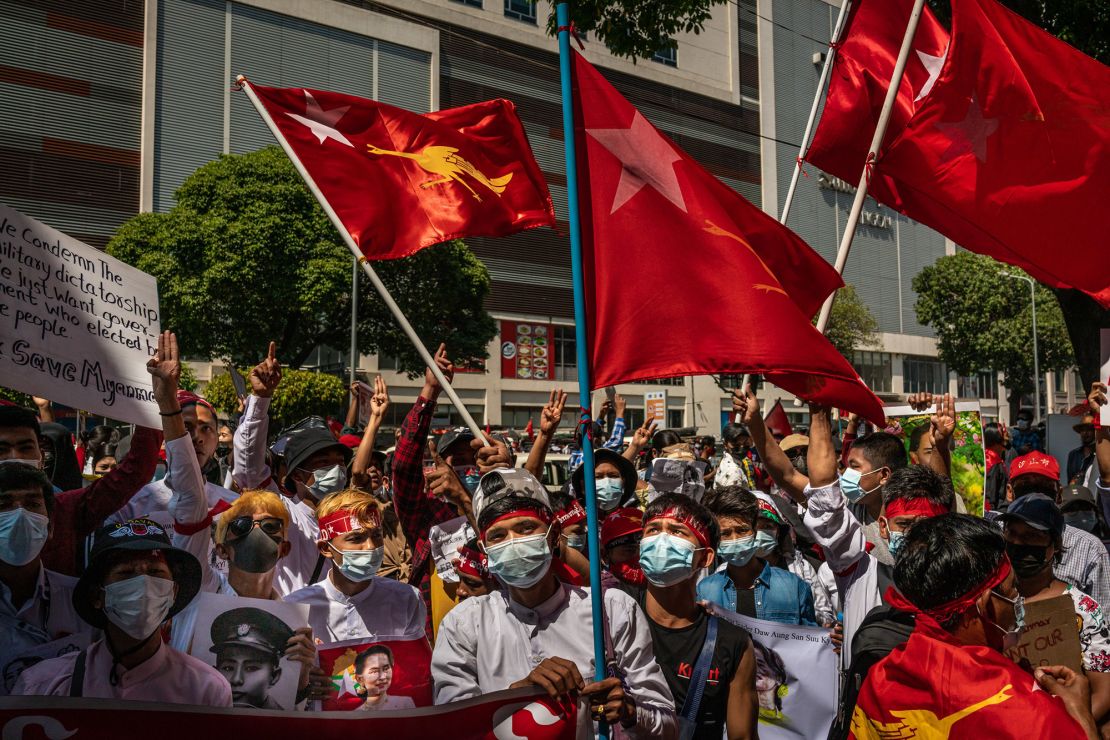 Protesters hold placards and shout slogans near the City Hall on February 13, 2021 in Yangon, Myanmar. 