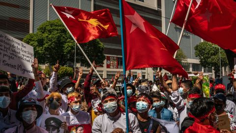 Protesters hold placards and shout slogans near the City Hall on February 13, 2021 in Yangon, Myanmar.