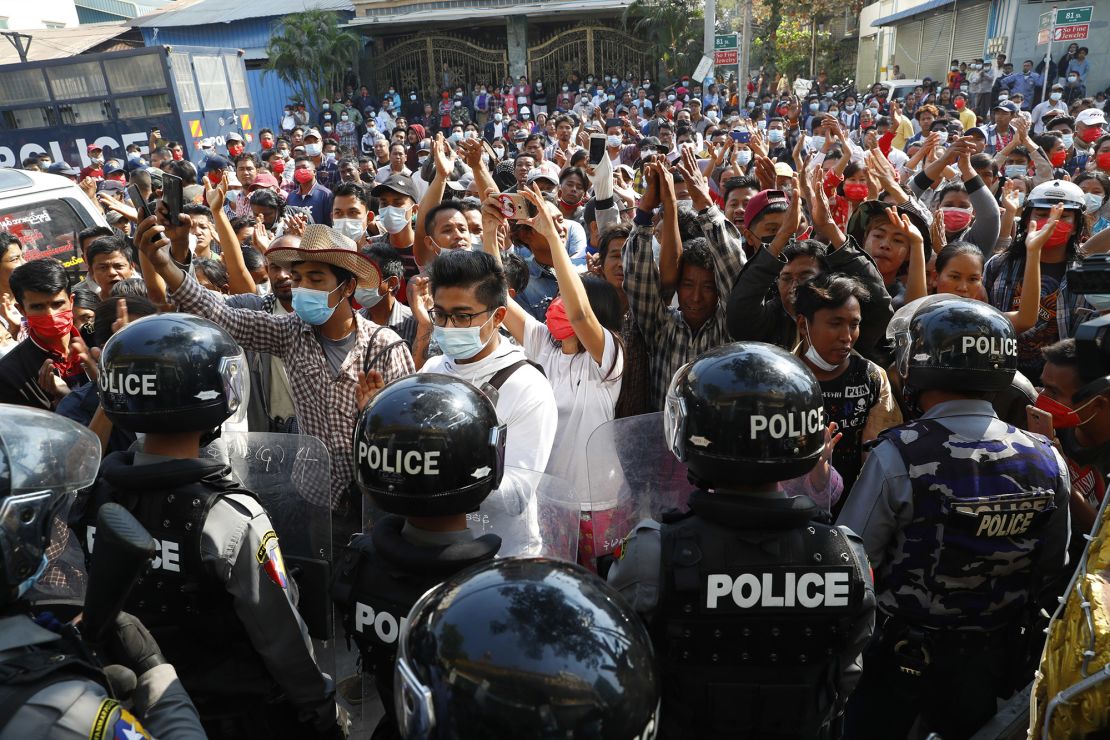 Residents and protesters face riot police as they question them about recent arrests made in Mandalay, Myanmar,  February 13, 2021. 