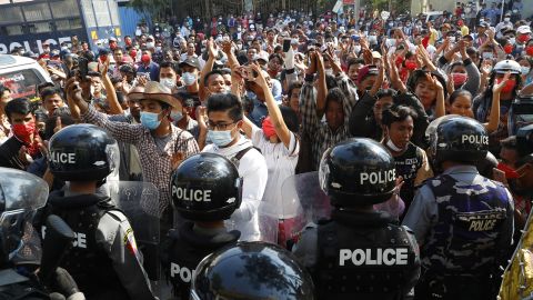 Residents and protesters face riot police as they question them about recent arrests made in Mandalay, Myanmar, February 13, 2021.