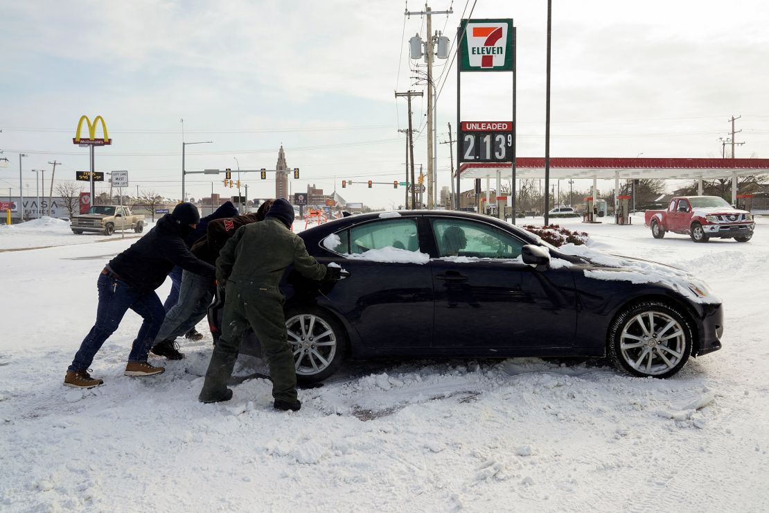 People work to free a stuck motorist in Oklahoma City on February 15, 2021.