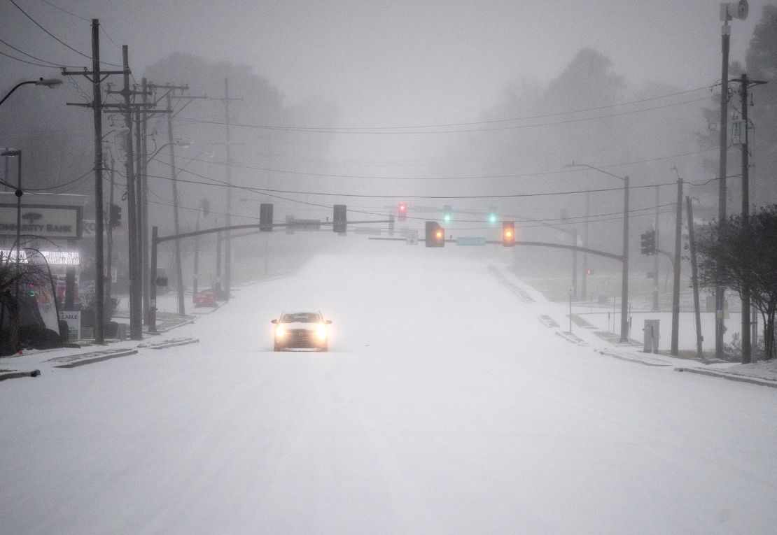 A car drives slow during the snowfall near Old Canton Road in Ridgeland, Mississippi on February 15, 2021.
