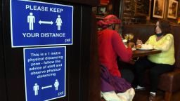 A sign outlining social distancing is displayed near customers in Jackson's Bar in the city centre of Glasgow on October 8, 2020, on the eve of a two-week closure of pubs due to an increase in the number of cases of the novel coronavirus COVID-19. - Scotland, on October 7, 2020, ordered a two-week closure of pubs in the central part of the country including the main cities Glasgow and Edinburgh.  First Minister Nicola Sturgeon said the measures, to last for 16 days from October 9, were designed as "short, sharp action to arrest the worrying increase in infection". (Photo by Andy Buchanan / AFP) (Photo by ANDY BUCHANAN/AFP via Getty Images)