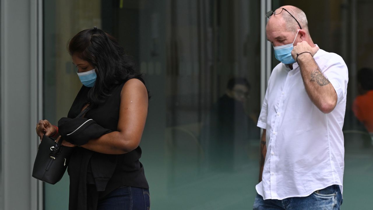 British national Nigel Skea (R) and his wife Agatha Maghesh Eyamalai arrive at the State Court in Singapore on February 15, 2021, where they faced charges of breaching the Covid-19 coronavirus stay home regulations.