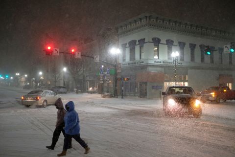 Two women cross Main Street as snow falls in Bowling Green, Ohio, on Monday.