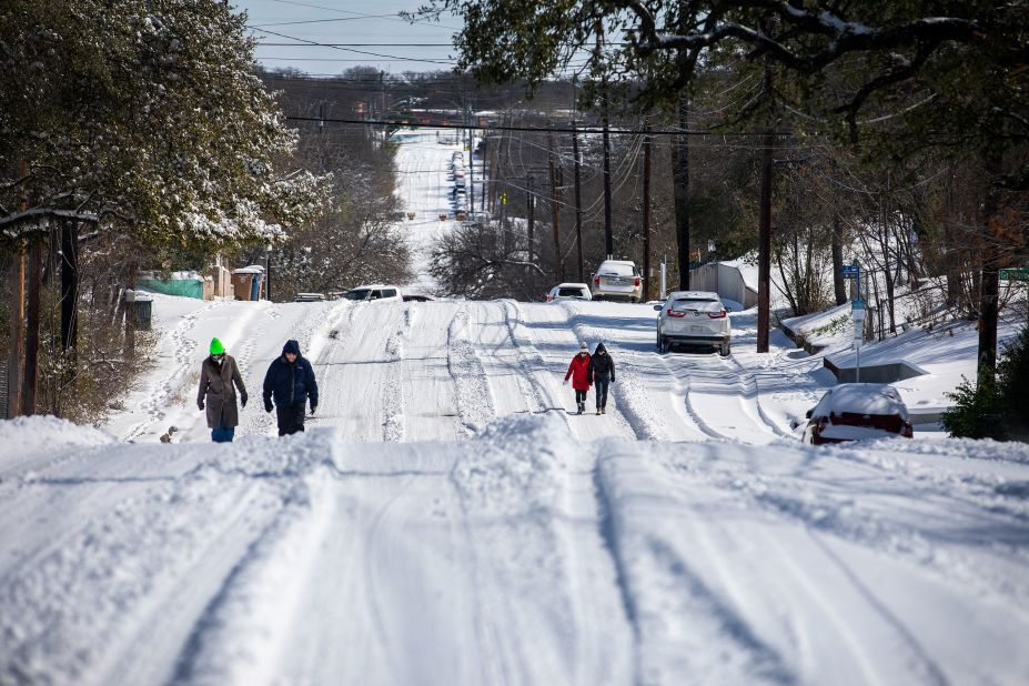 People walk on a snowy road in Austin on Monday.