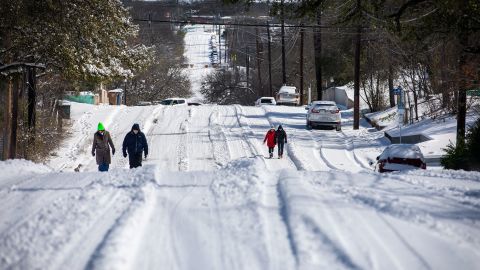 Pedestrians walk on an icy road on Monday, February 15, in East Austin, Texas. 
