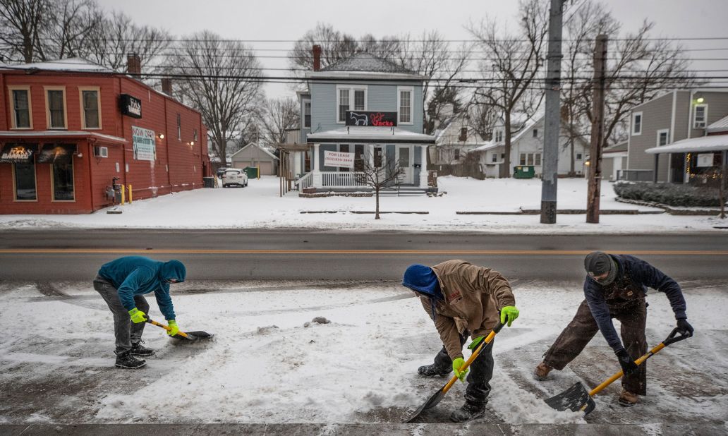 Men shovel ice and snow in front of shops in Louisville, Kentucky, on Monday.