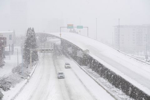 Cars drive along Interstate 705 as snow falls in Tacoma, Washington, on Saturday.