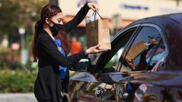 CITY OF COMMERCE, CALIFORNIA - FEBRUARY 11: An employee delivers merchandise to a customer during the Citadel Outlets' Drive-Thru Pop-Up Valentine's Day Boutique on February 11, 2021 in City of Commerce, California. (Photo by Rich Fury/Getty Images)