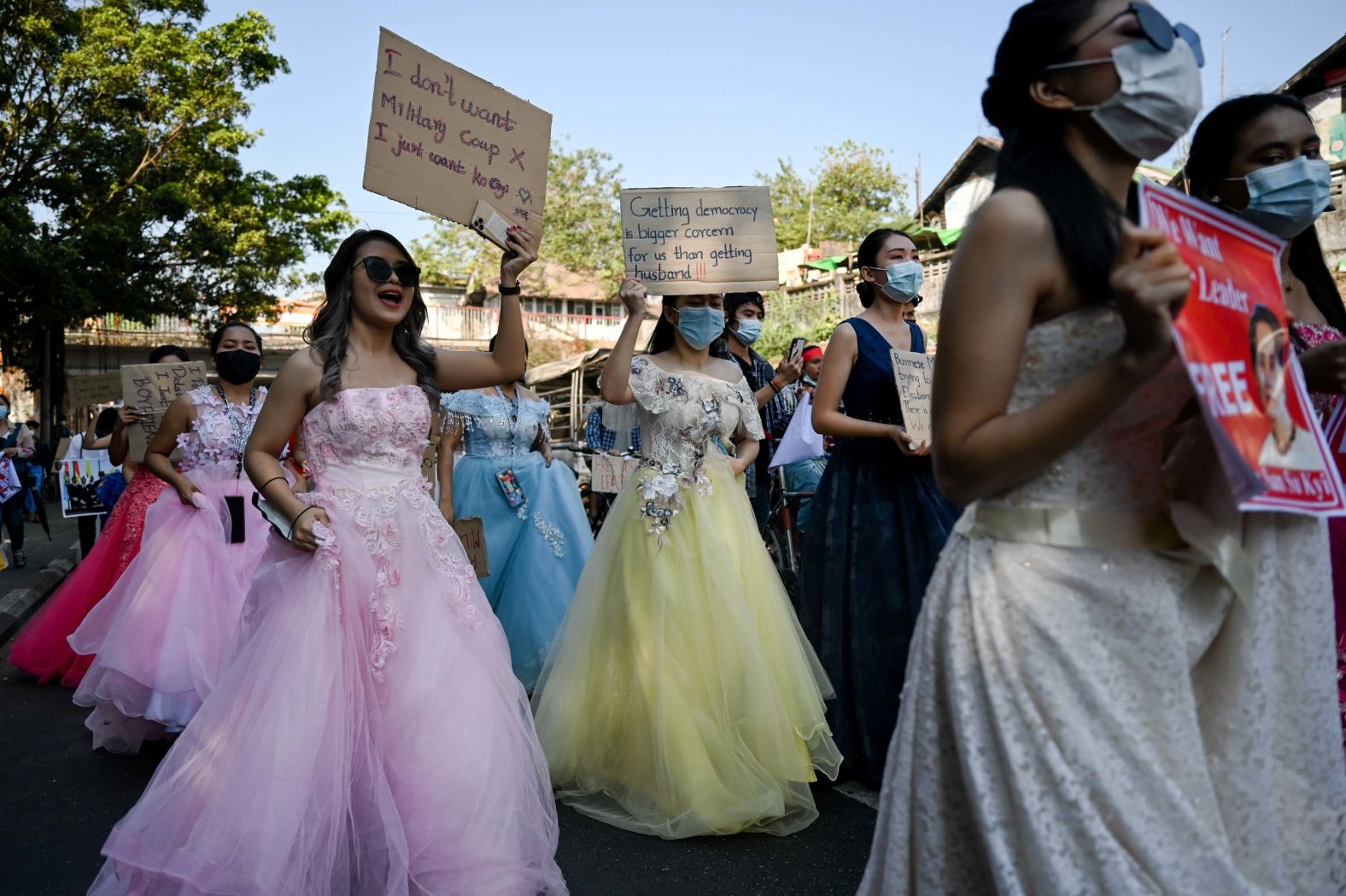 Women in wedding gowns holds up anti-coup placards in Yangon on February 10.