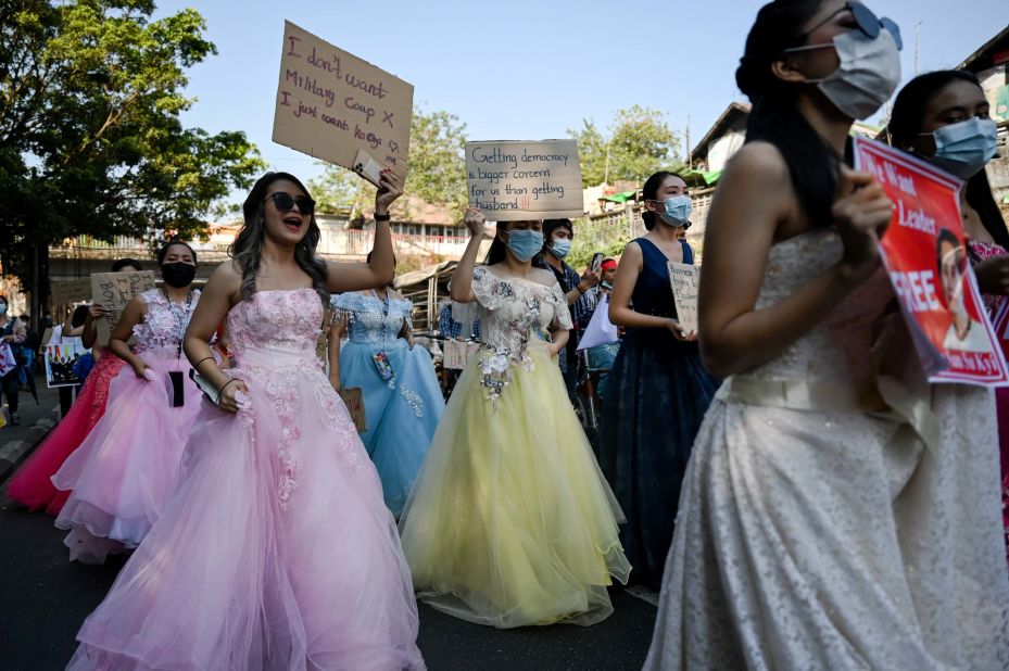 Women in wedding gowns holds up anti-coup placards in Yangon on February 10.