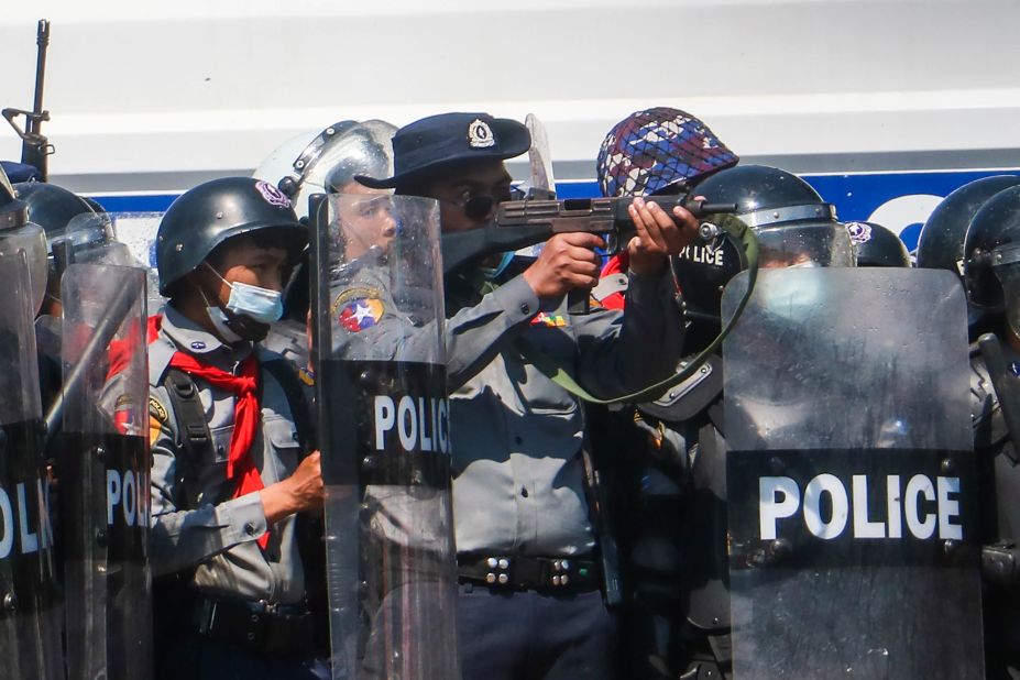 A police officer aims a gun during clashes with protesters in the capital of Naypyidaw on February 9.