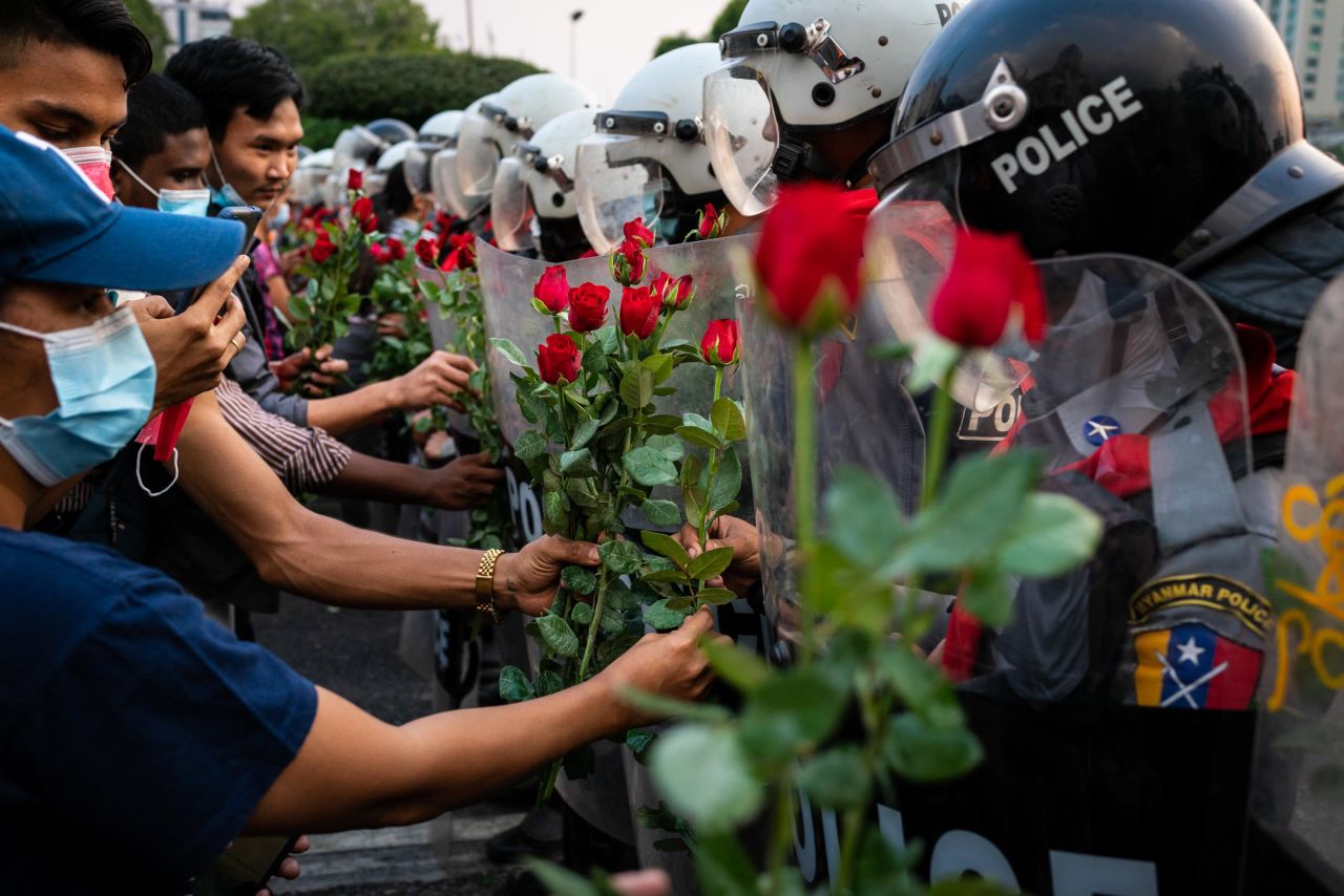 Protesters give roses to riot police in Yangon on February 6.