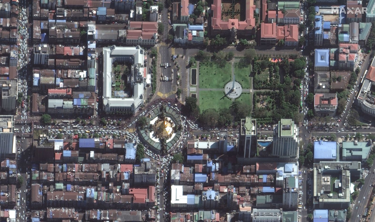 A powerful picture from that same day in Yangon shows a crowd of protestors amassing near the city hall. A crowd of hundreds appears gathered between the Sule Pagoda, Maha Bandula Park, and City Hall.  More than a dozen large vehicles, which appear to be army trucks and police water cannons, block the road facing City Hall.